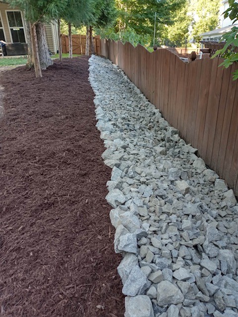 Rock drainage bed next to wooden fence